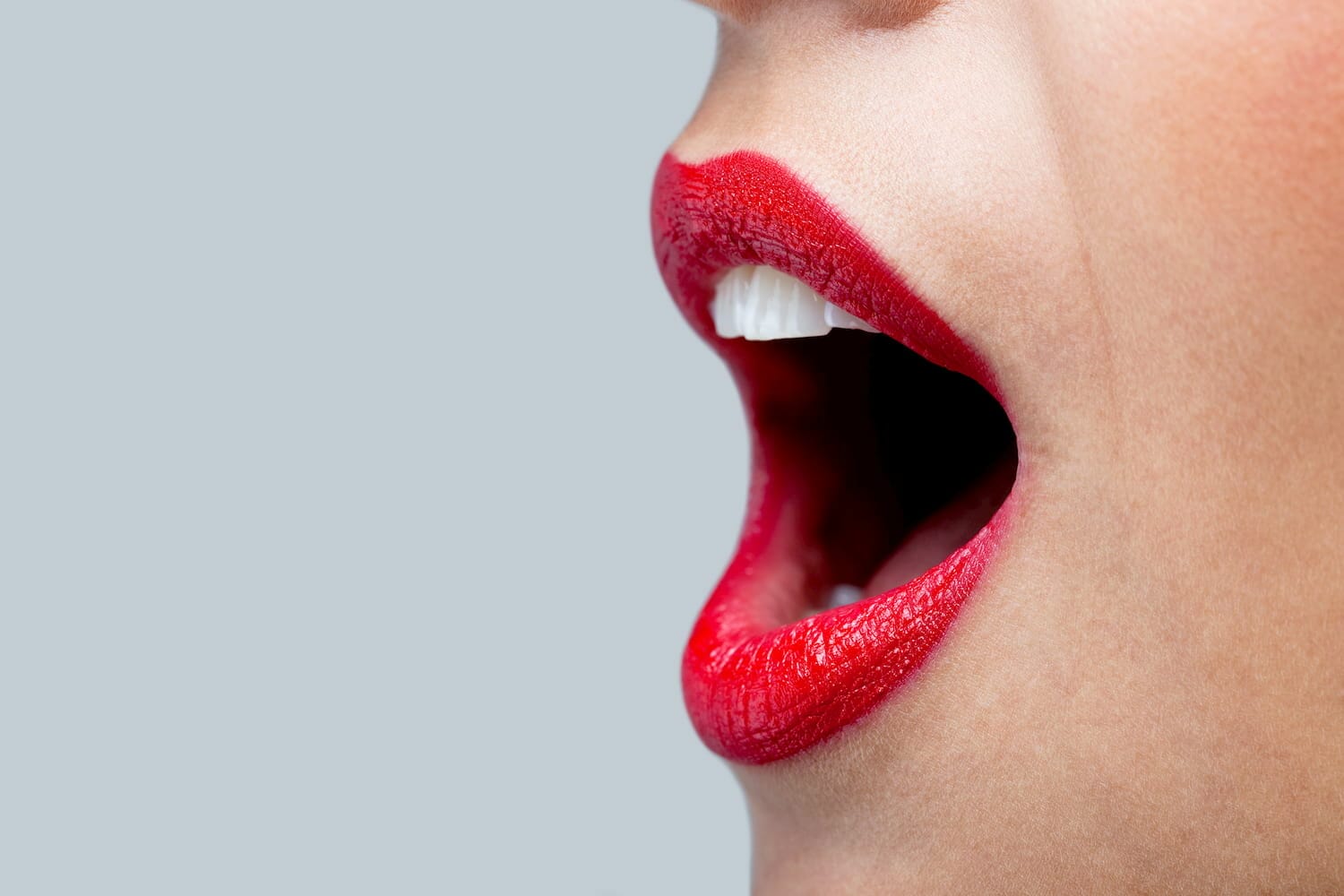 a close up of a woman wearing red lipstick with her mouth open